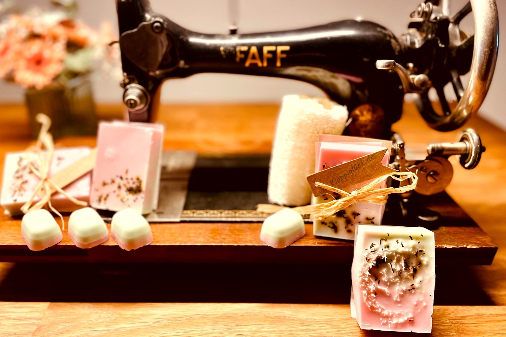 Antike Nähmaschine mit rosa Seifen und dekorativen Elementen.